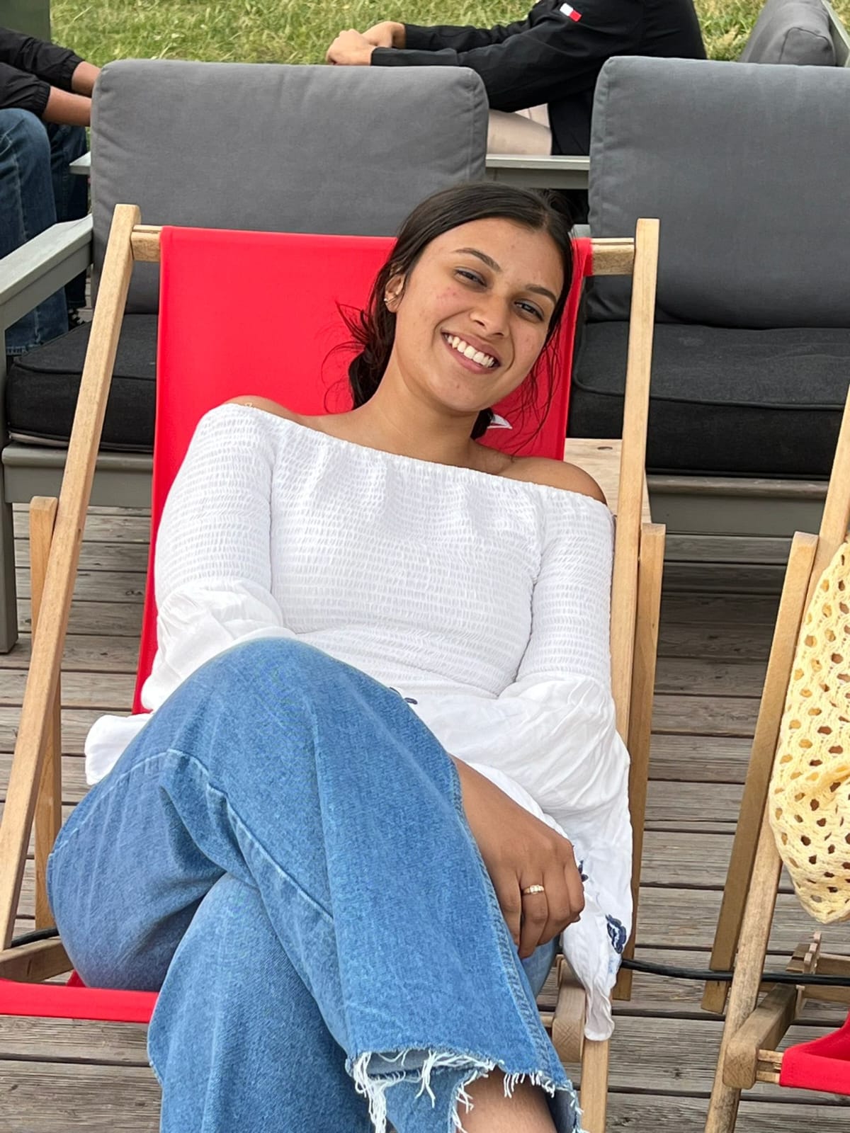 Aarushi relaxing in a red deck chair outdoors, smiling easily at the camera.