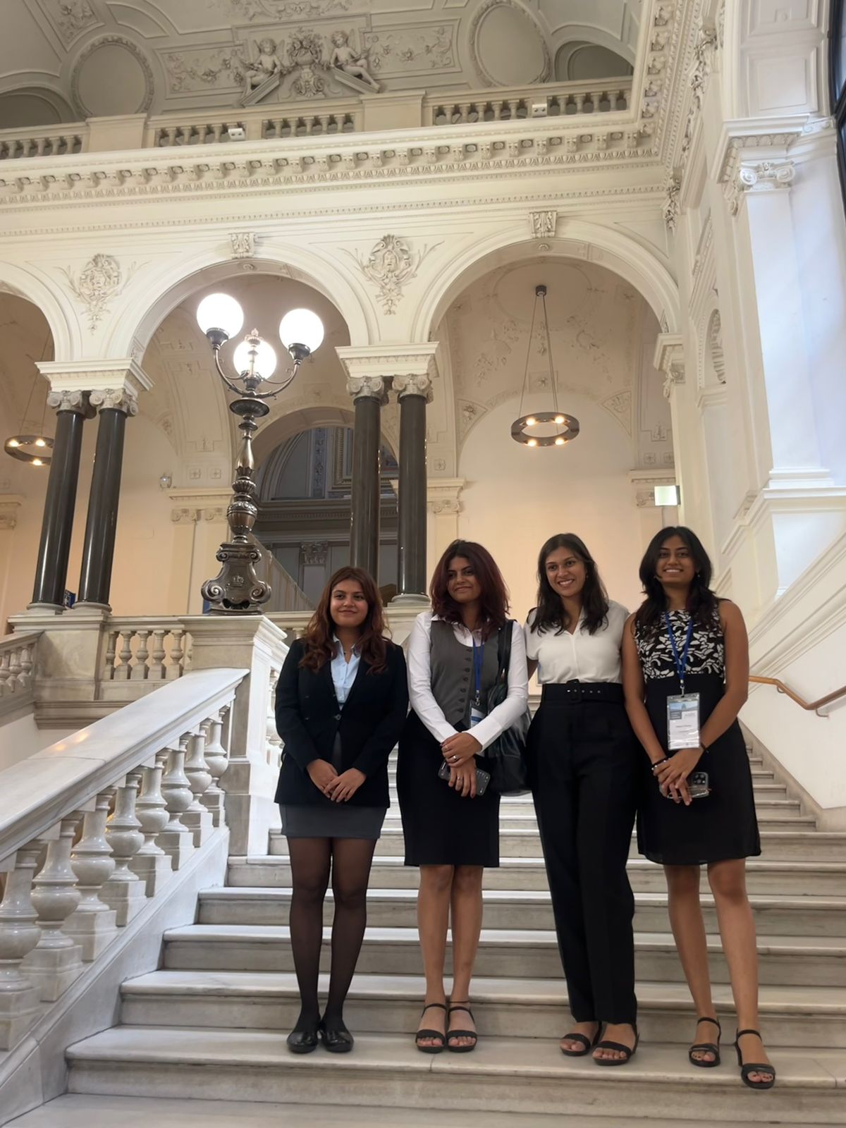Aarushi with her moot team on a grand marble staircase in Vienna, dressed formally, representing India.