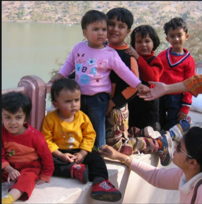 Aarushi as a small child with her cousins, gathered on a ledge by a lake.